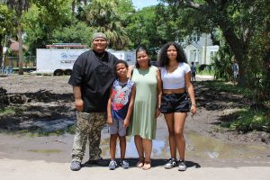 Family of four standing in front of future home site