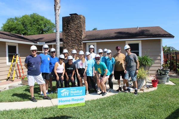 Group of volunteers gather in front of home being repaired