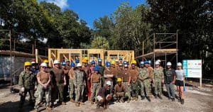 Group photo of Navy volunteers with homeowner at construction site