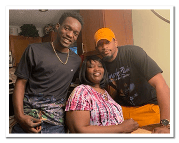 Mother sits with two sons standing behind her